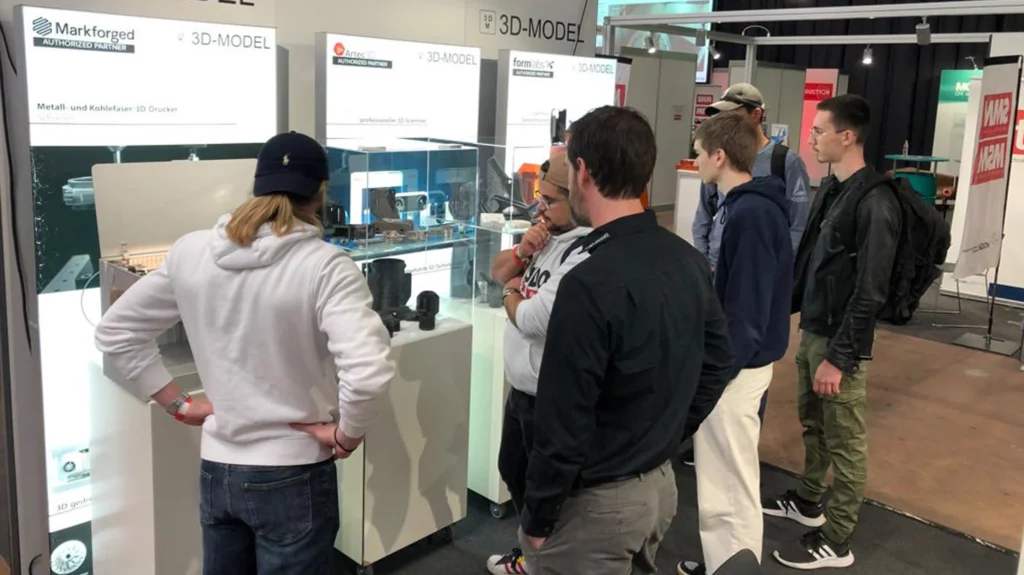 Besucher schauen sich 3D-Drucker und 3D-Scanner für die Fertigung auf dem Messestand von 3D-MODEL beim Swiss Production Forum an